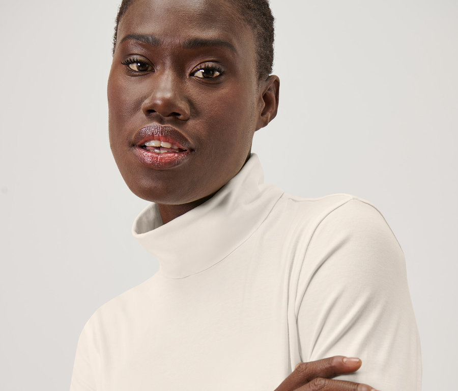 Krem beyaz balıkçı yaka tişört giyen bir kadının portresi.