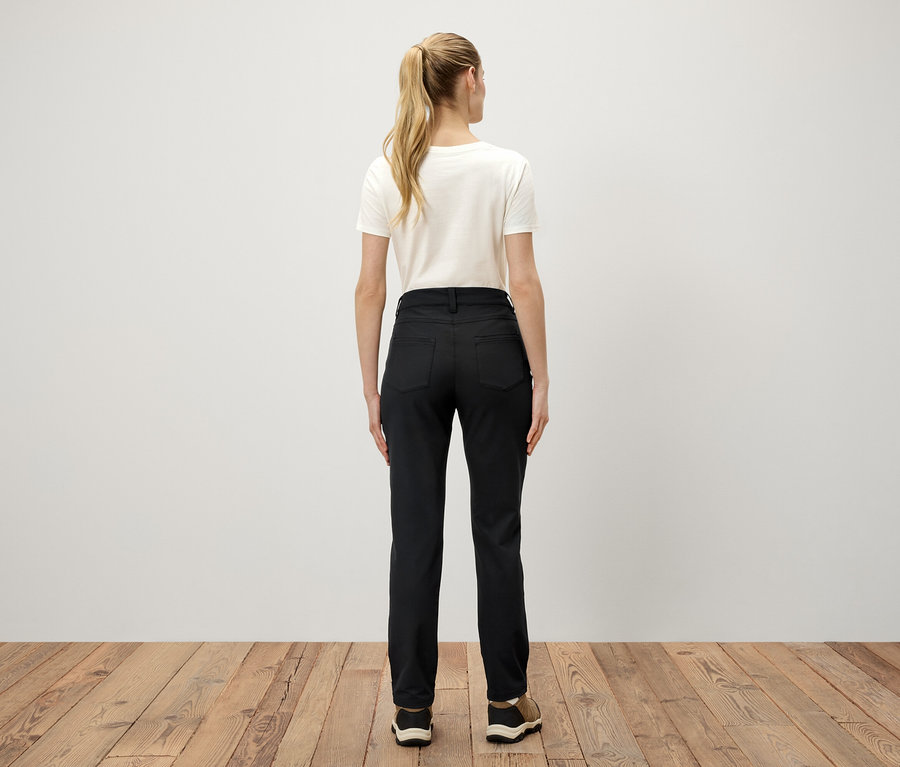 Atkuyruğu yapılmış sarı saçlı, beyaz tişört ve siyah pantolon giyen bir kadının arka görüntüsü.