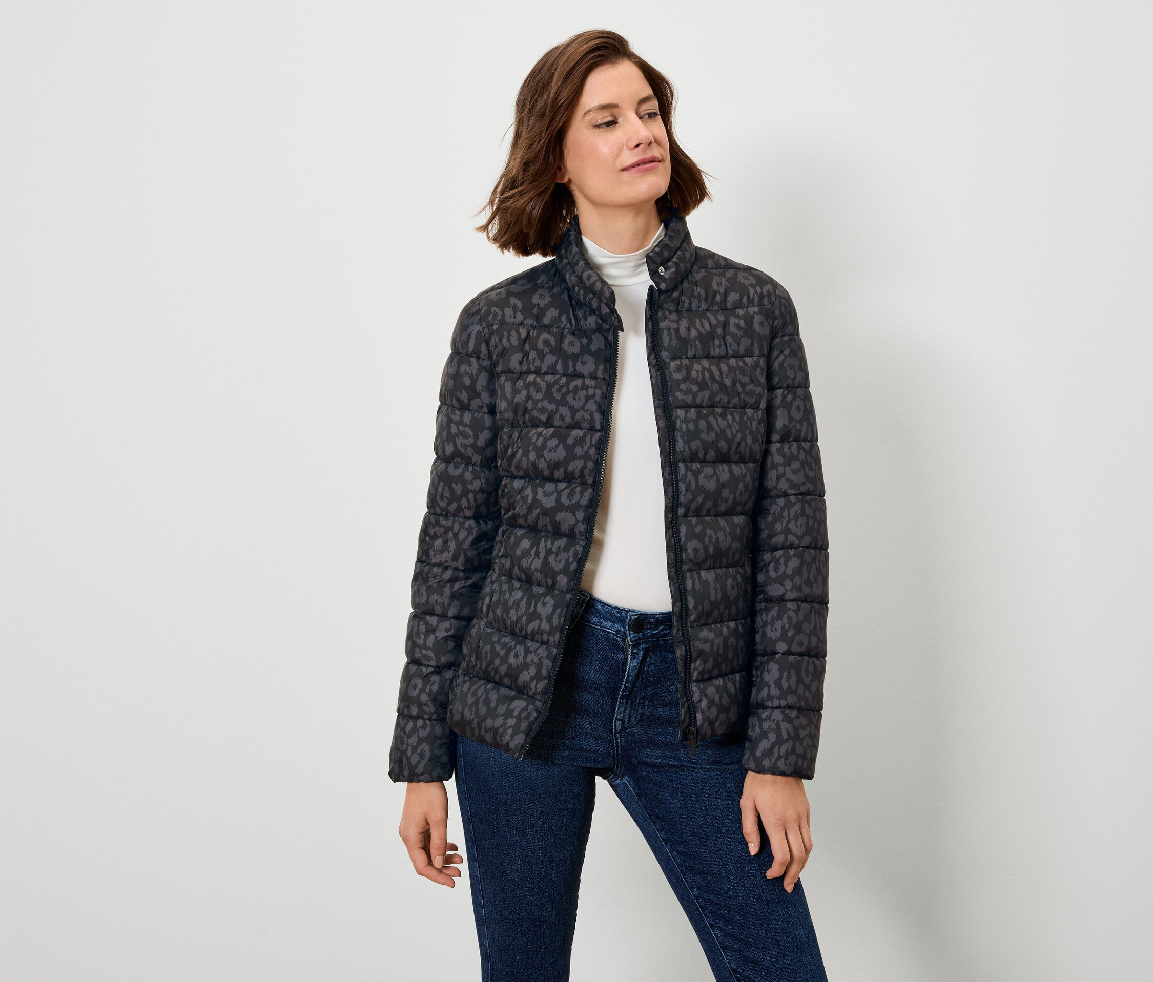 Kadın desenli siyah şişme mont ve kot pantolon giyiyor.