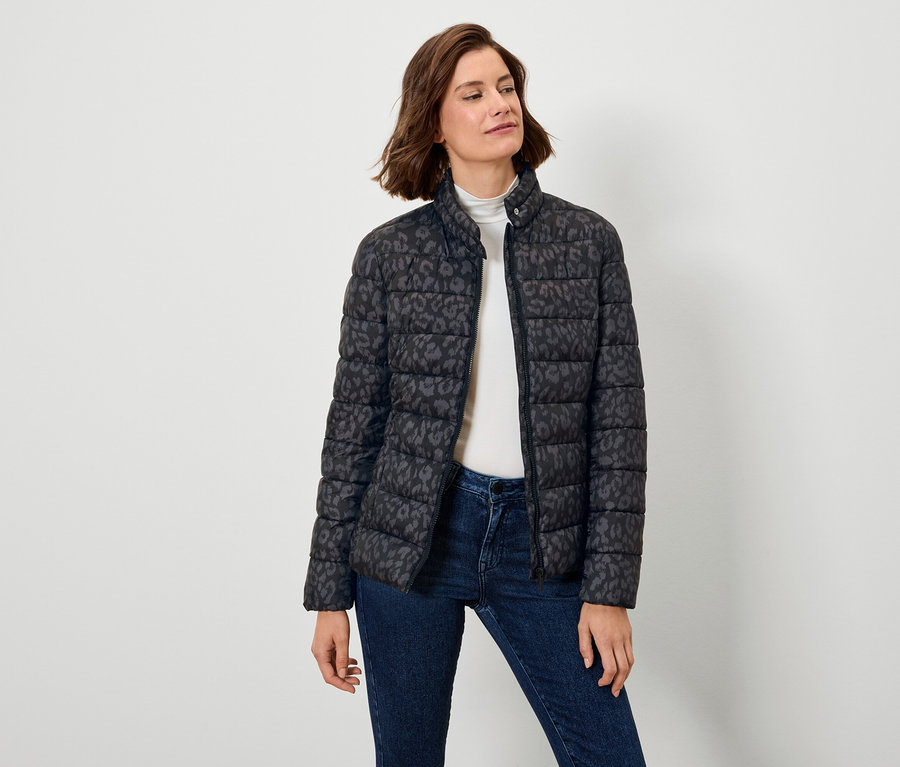 Kadın desenli siyah şişme mont ve kot pantolon giyiyor.