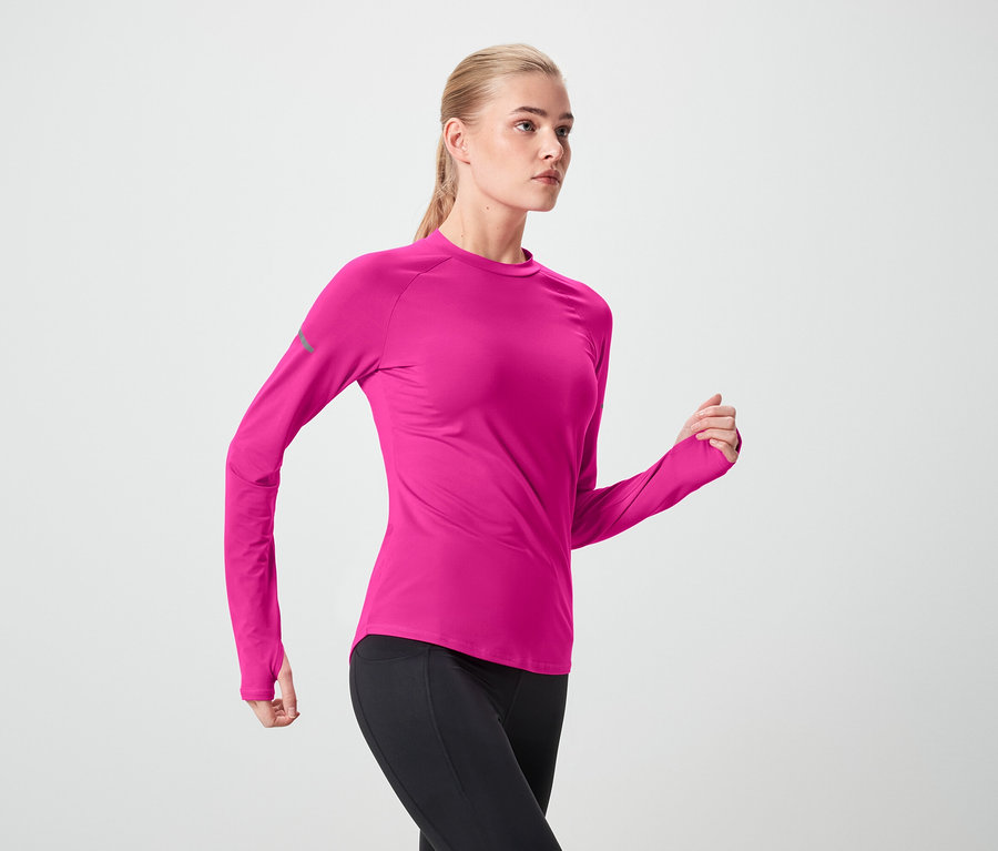 Pembe spor üstü ve siyah taytlı kadın hareket halinde.