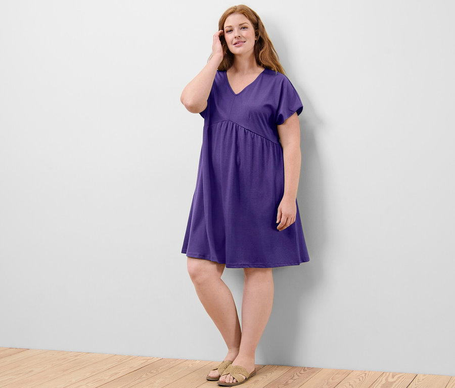 Kadın mor renkli jarse elbise ile poz veriyor.