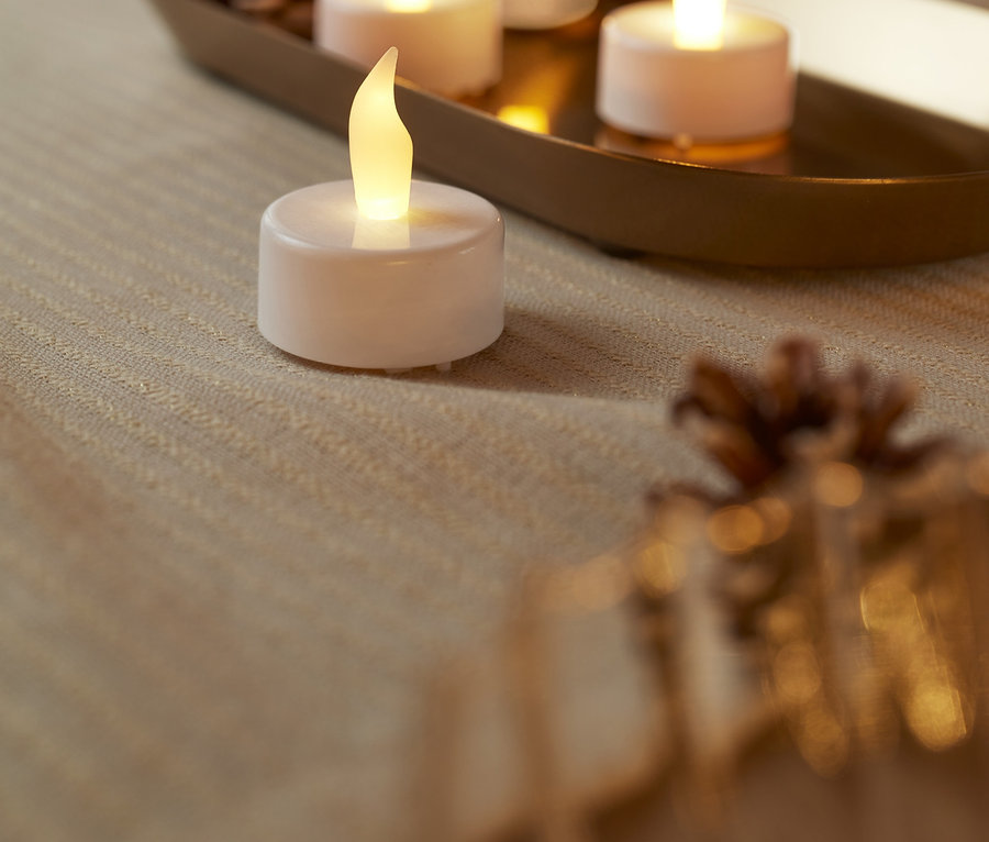 Masa üzerinde dört adet beyaz LED tealight mum.