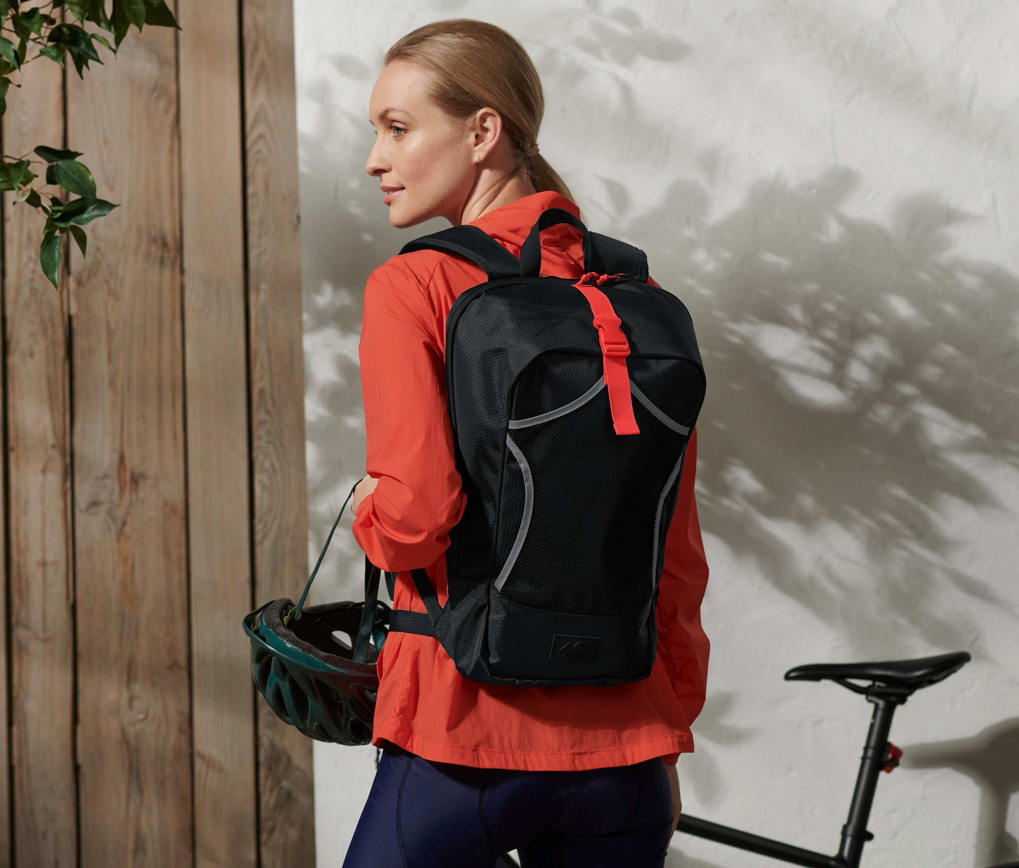 Kadın bir bisiklet sırt çantası takıyor ve bir kask tutuyor.