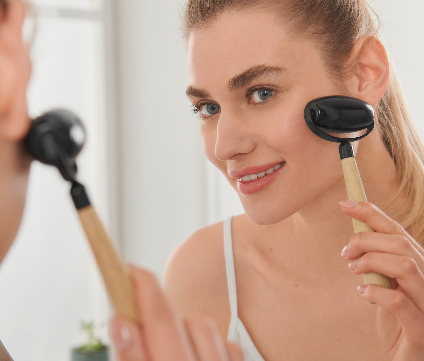 Kadın yüzünde Yüz Masaj Rulosu, Obsidyen, kullanıyor.