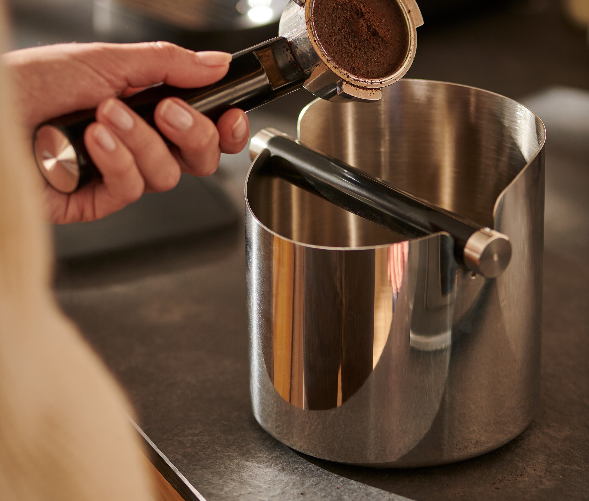 El kahve filtresini parlak kahve posa kutusunun üzerinde tutuyor.