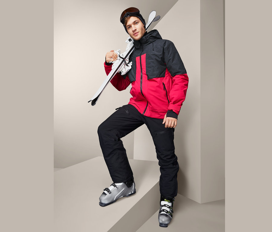 Omzunda kayaklarla High-End Kayak Montu giyen adam.