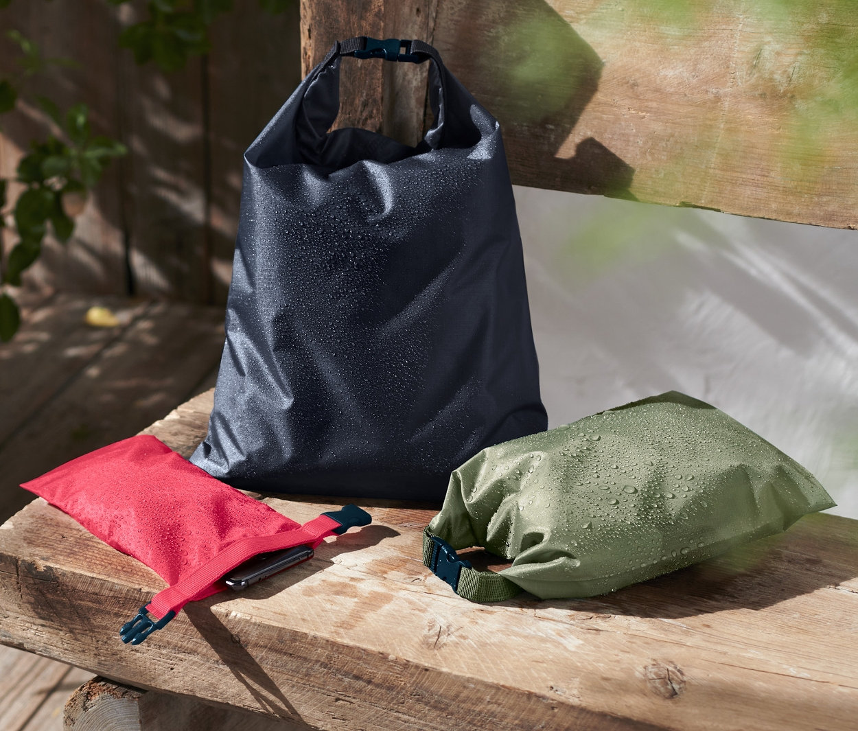 Tahta bir bankta duran üç adet su geçirmez torba.