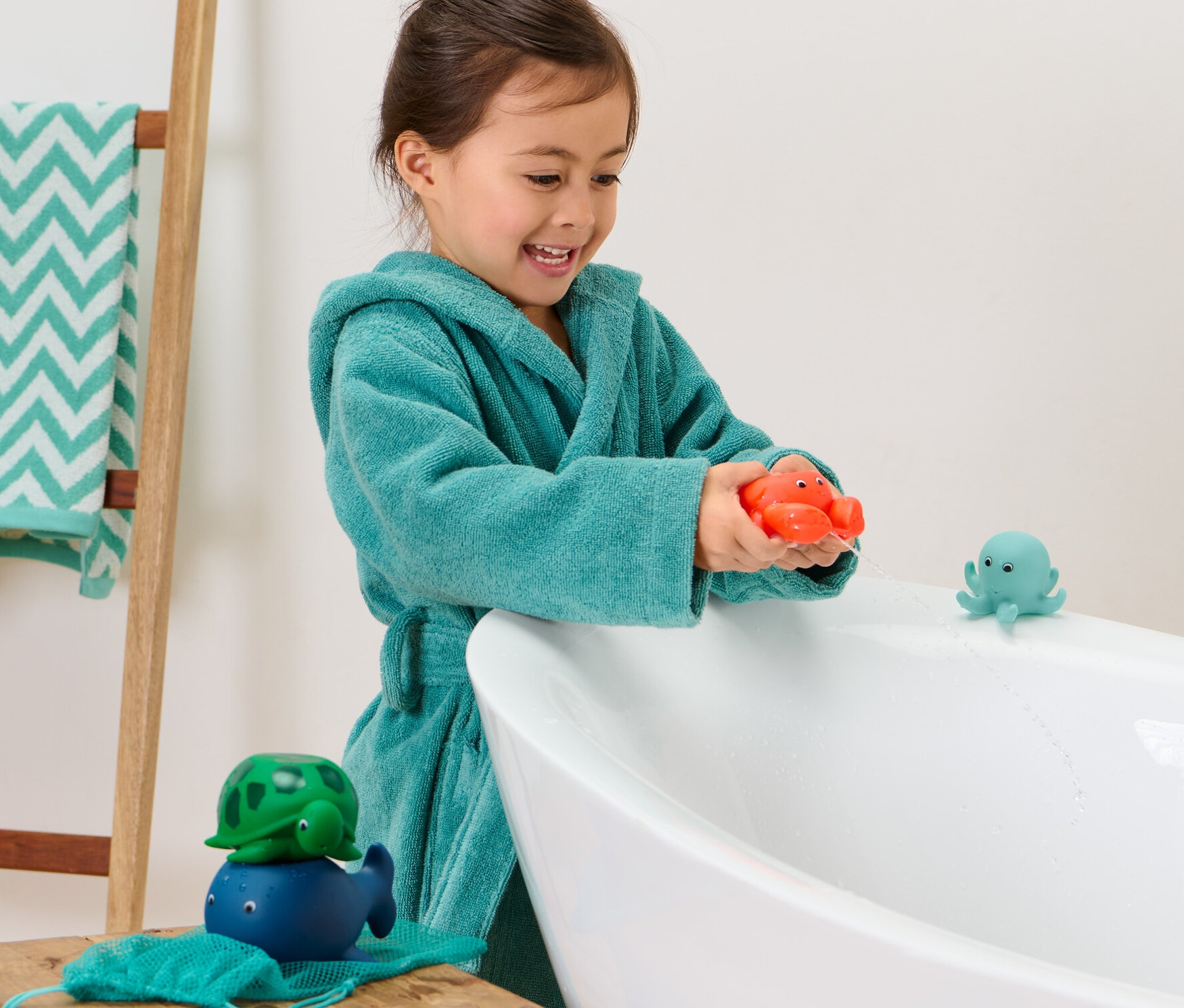 Bornozlu bir kız çocuğu küvette 4 Adet Su Fışkırtan Hayvan ile oynuyor.