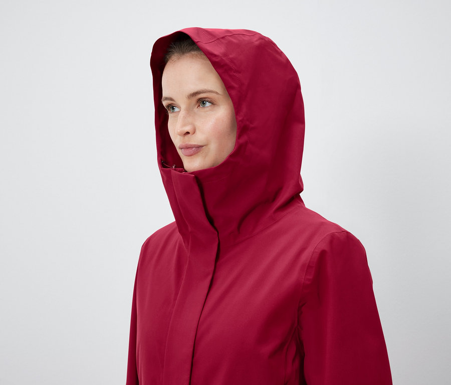 Kadın kapüşonlu kırmızı bir ceket giyiyor.