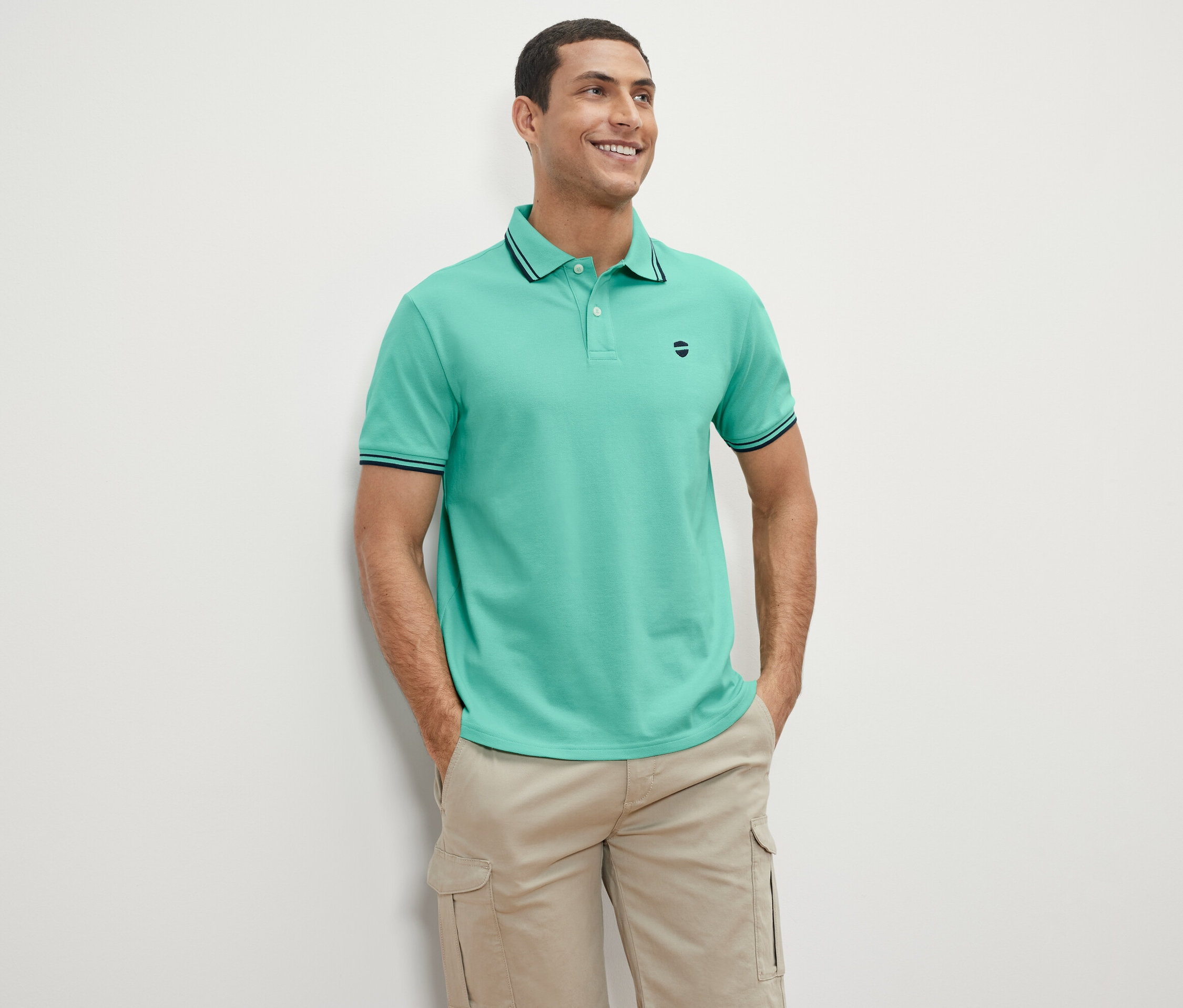 Ayakta duran ve gülümseyen bir adam yeşil Pike Polo Yaka Tişört giyiyor.