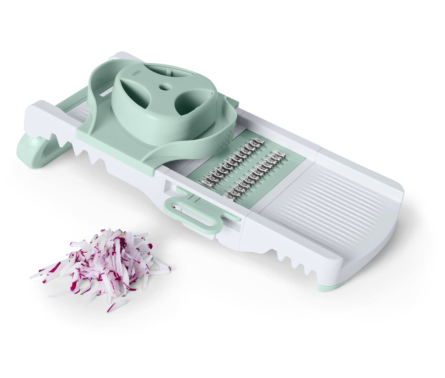 Doğranmış kırmızı soğanların yanında, açık yeşil detaylara sahip beyaz bir sebze dilimleyici.