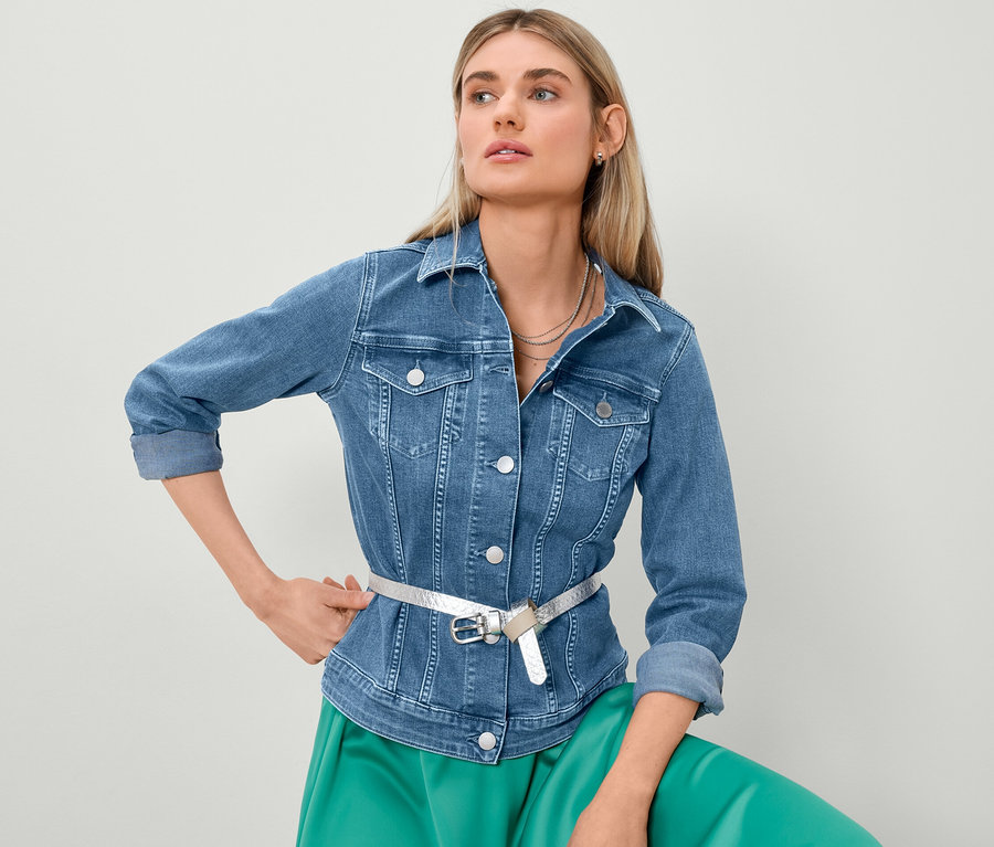 Sarışın bir kadın kot ceket ve saten etekle poz veriyor