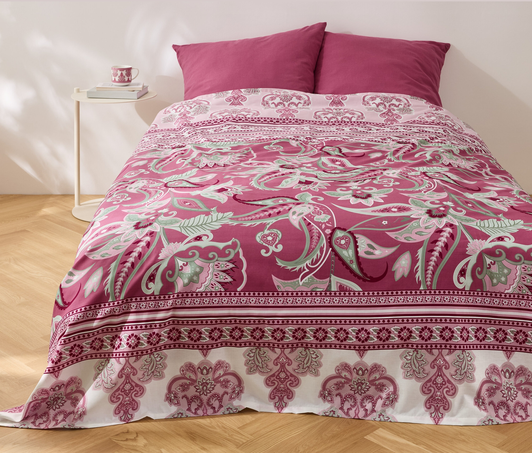 Çiçek desenli Renforcé-Multifunktions-Überwurf yatak örtüsü ve iki yastıklı bir yatak.