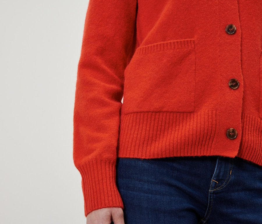 Kahverengi düğmeli kırmızı hırka ve mavi kot pantolon.