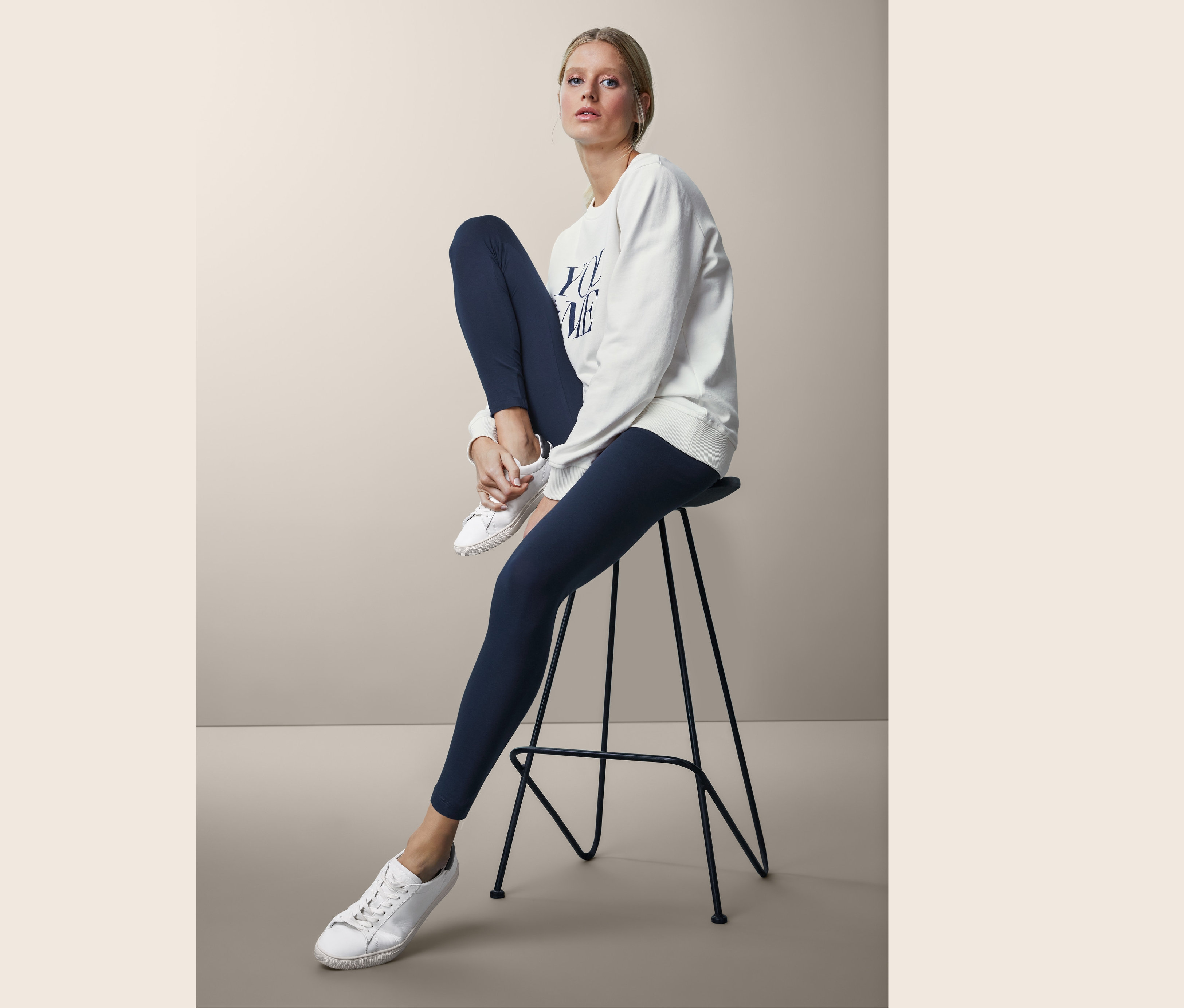 Kadın taburede oturuyor, üzerinde Organik Pamuklu Tayt var.