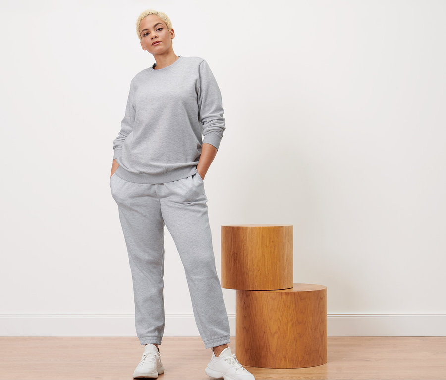 Kadın gri melanj eşofman altı ve sweatshirt ile poz veriyor.
