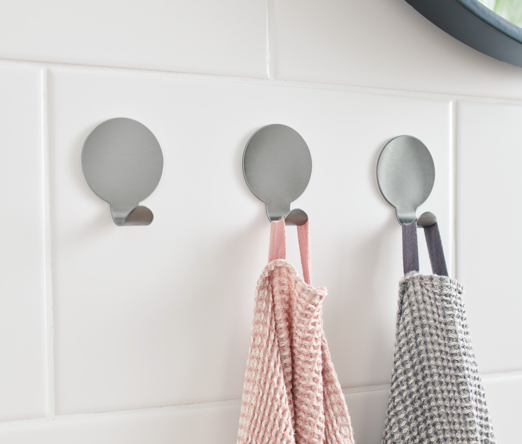 Beyaz fayanslara üç gümüş kanca tutturulmuştur. İkisinde havlu asılıdır.