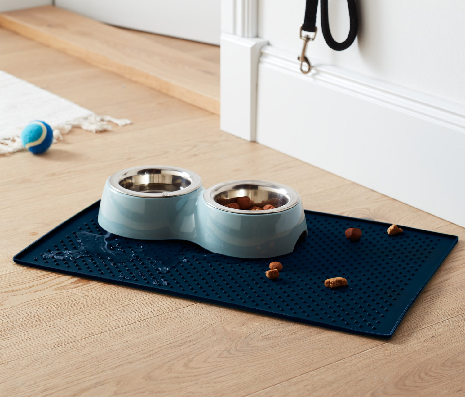 Ahşap zeminde, birinde mama olan iki paslanmaz çelik mama kabı bulunan mavi Mama Kabı Altlığı.