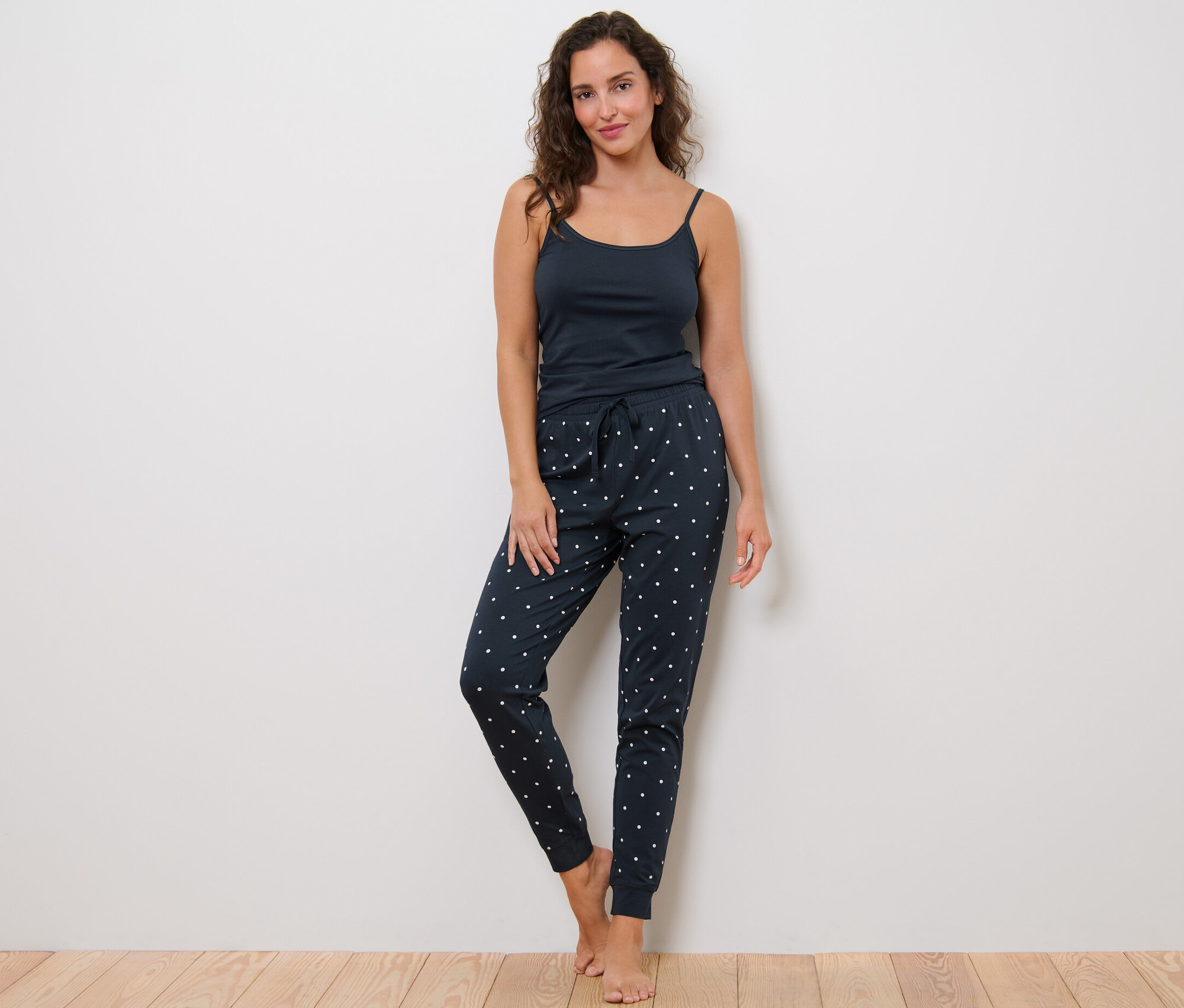 Kadın puantiyeli pijama altı ve atletle ayakta duruyor.