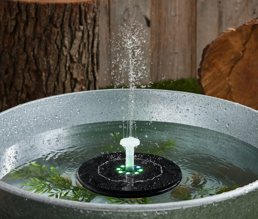 Su dolu bir küvette yüzen, ışıklı, güneş enerjili fıskiye.