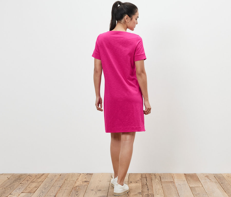 Kadın arkadan pembe jarse elbise giyiyor.