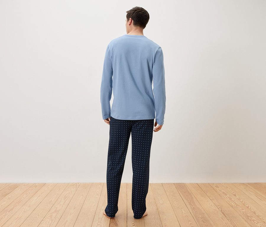 Açık mavi pijamalı ve koyu mavi pantolonlu bir adam arkadan görülüyor.