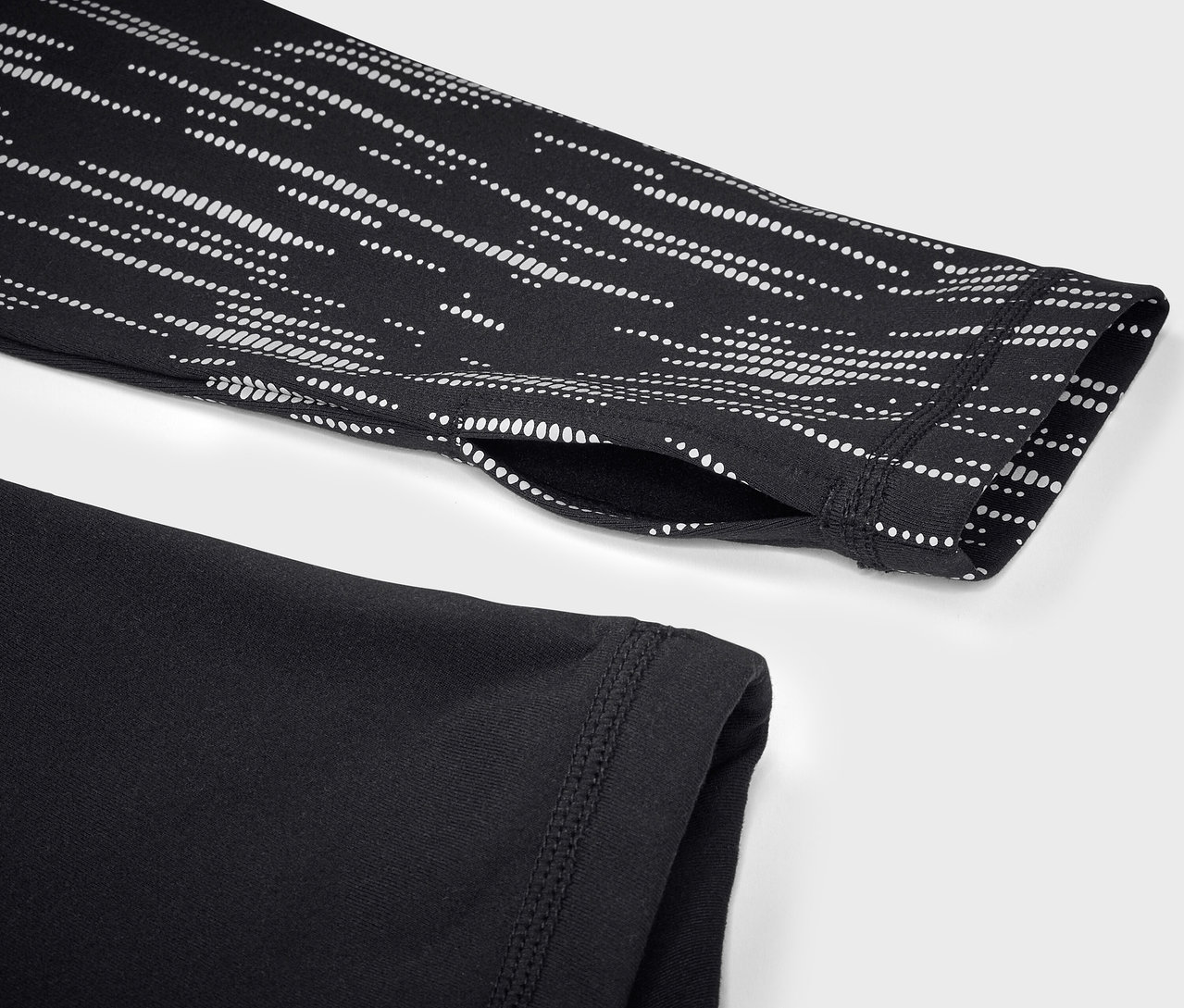 Kolunda beyaz geometrik deseni olan, siyah, uzun kollu bir spor üstünün yakın çekimi.