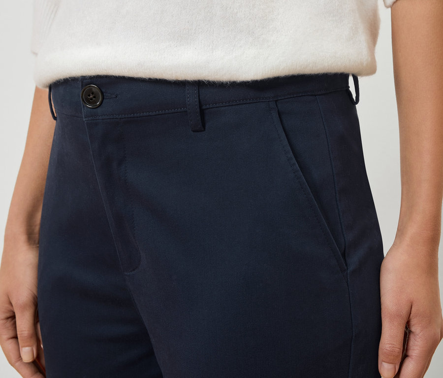 Lacivert pantolon ve beyaz kazak giyen bir kişinin yakın çekimi.