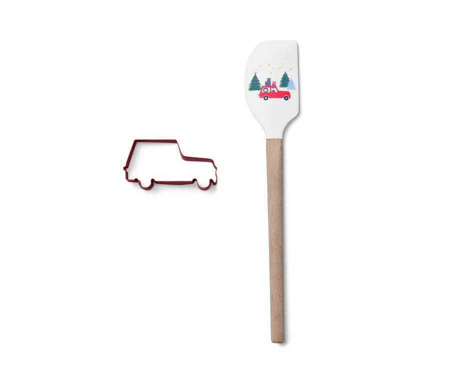 Kırmızı araba şeklinde kurabiye kalıbı, araba baskılı beyaz hamur spatulasının yanında duruyor.