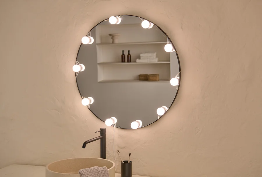 Lavabo, armatür ve LED'li USB Işık Zinciri olan yuvarlak aynalı banyo.