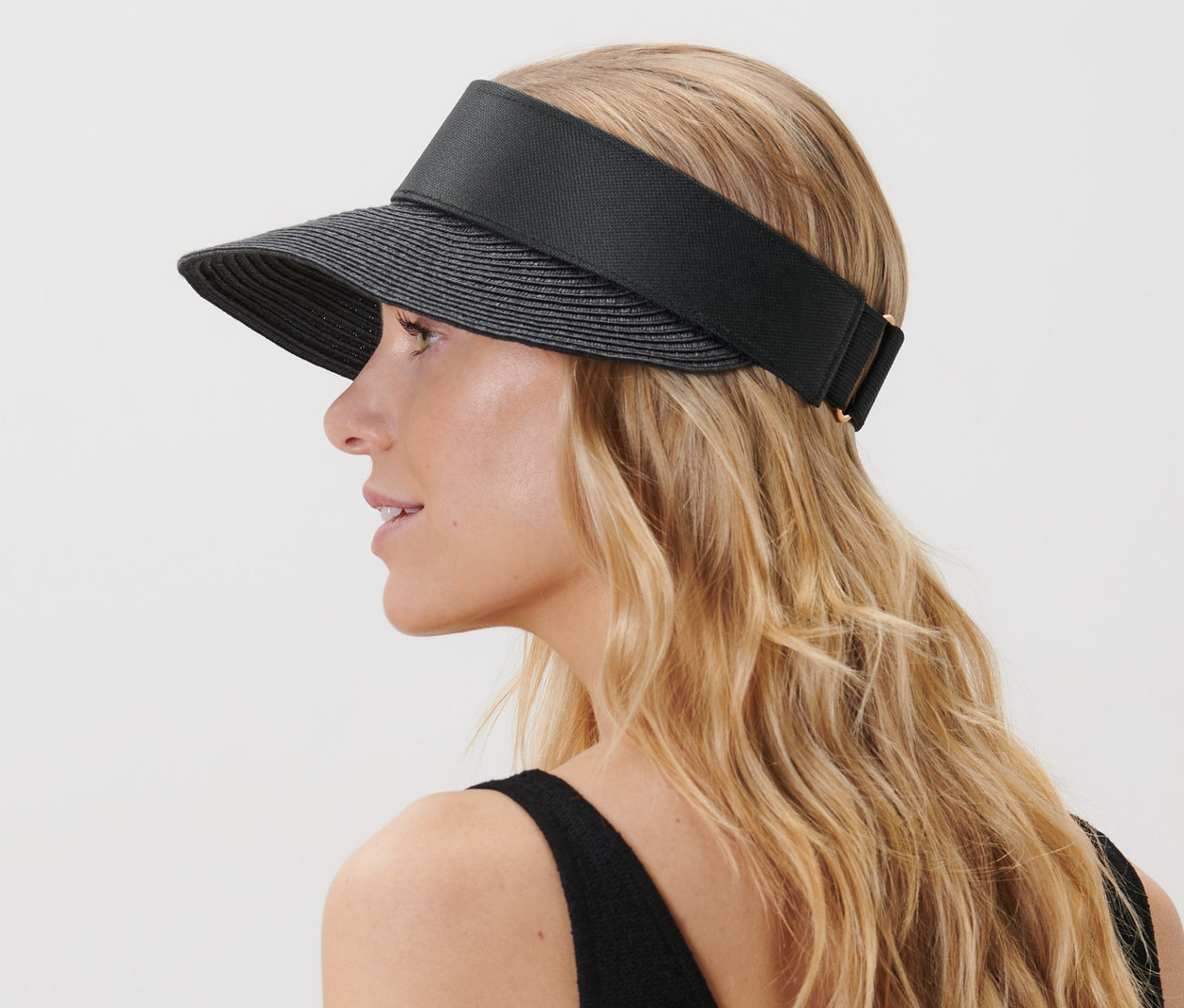 Sarışın saçlı bir kadın siyah vizör şapka takıyor.