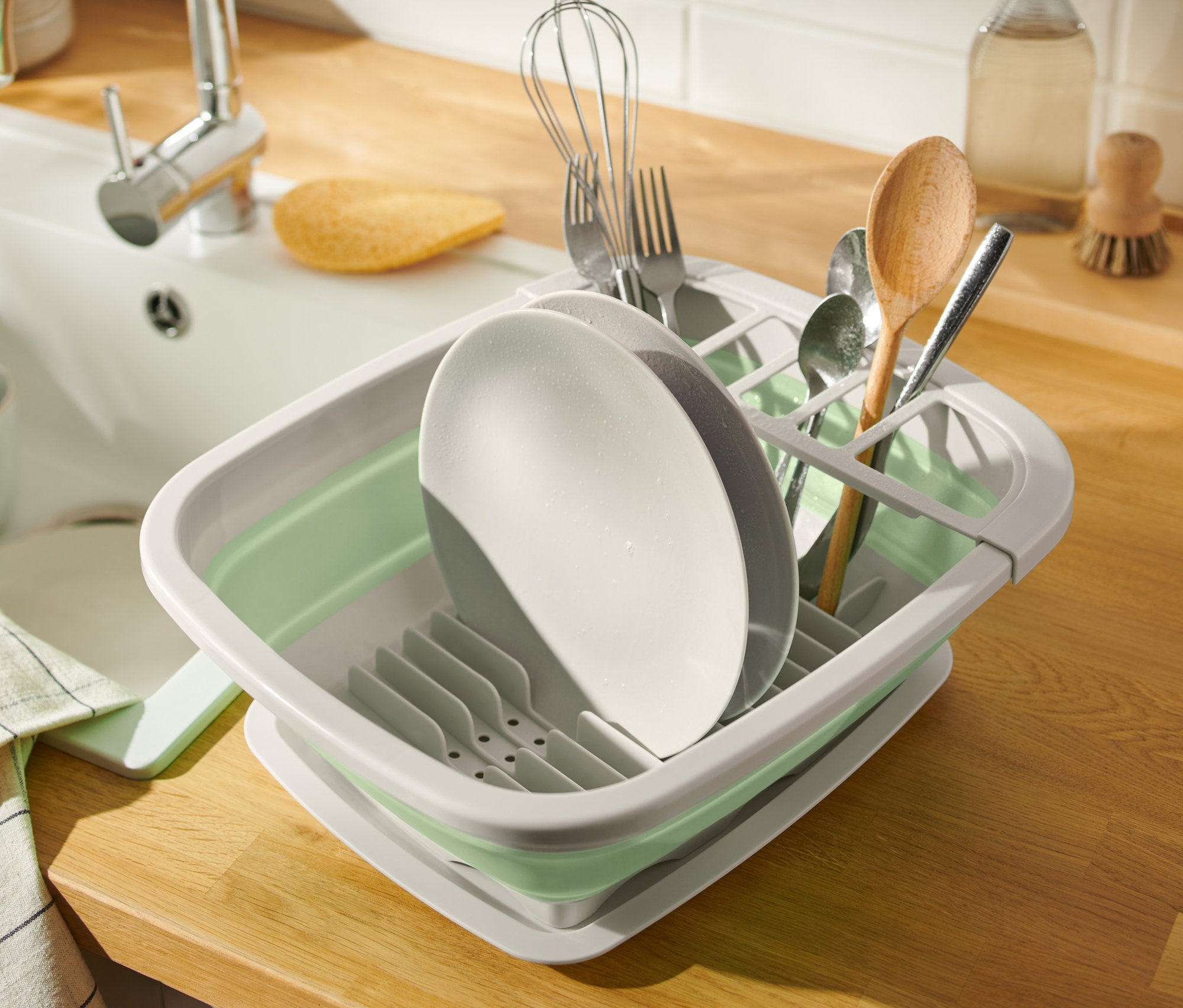 Lavabonun yanında katlanabilir bulaşıklık içinde bulaşıklar.