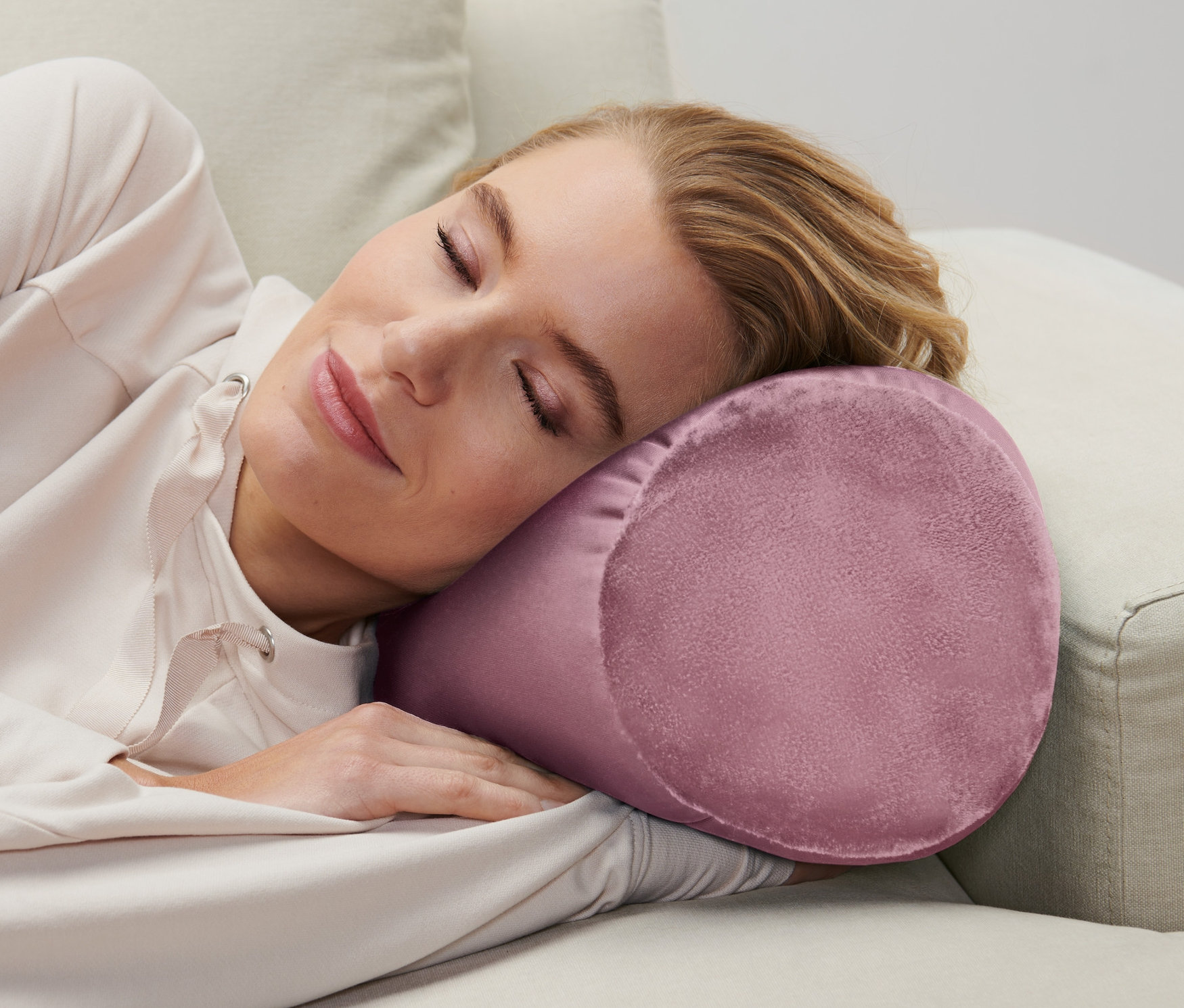 Kadın bej bir kanepede rahatlama yastığıyla uyuyor.