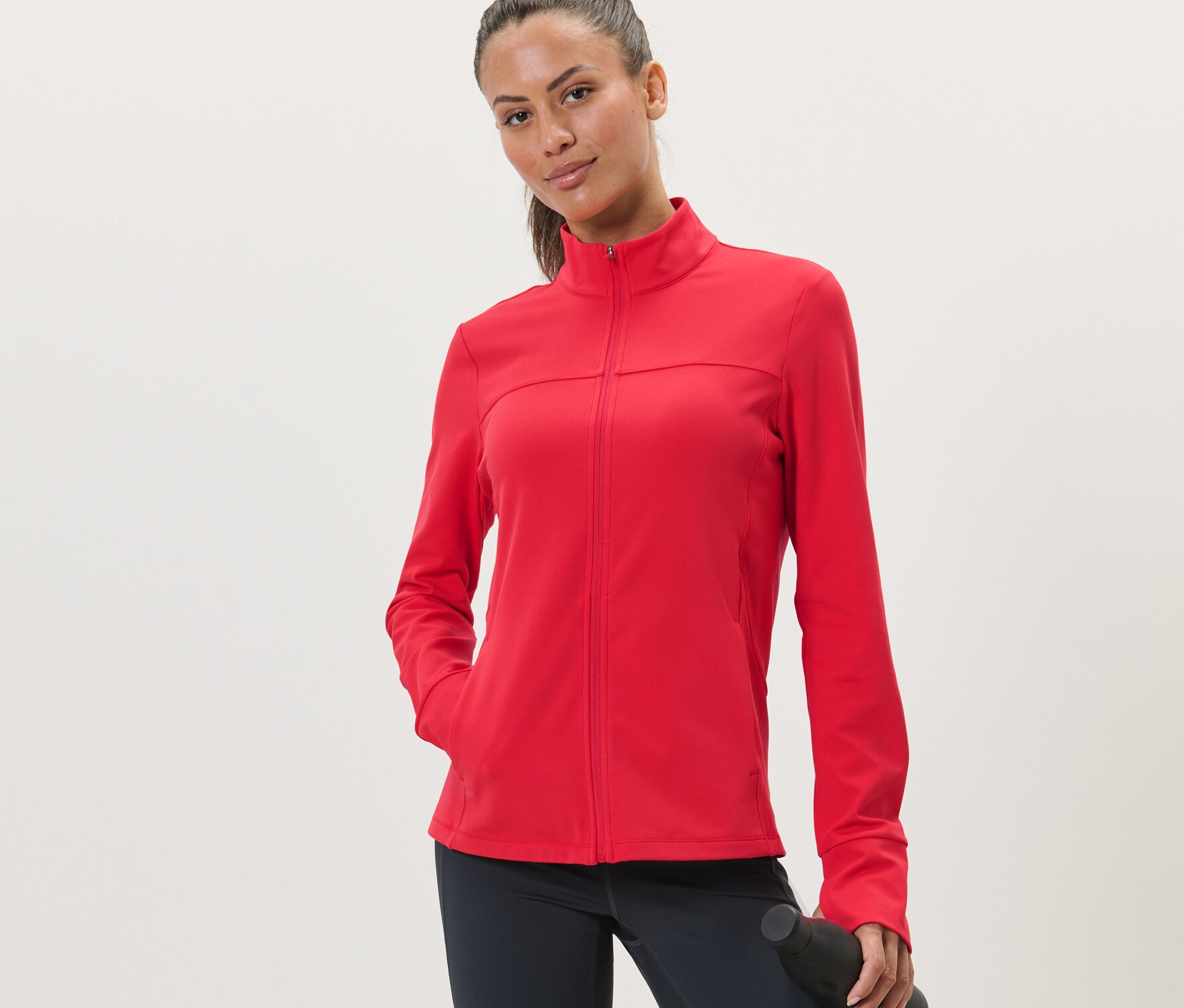 Kadın kırmızı bir spor montu giyiyor.