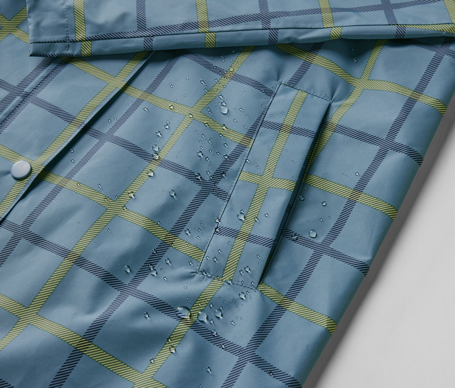 Su damlaları olan kareli mavi yağmurluk yakın çekimi.