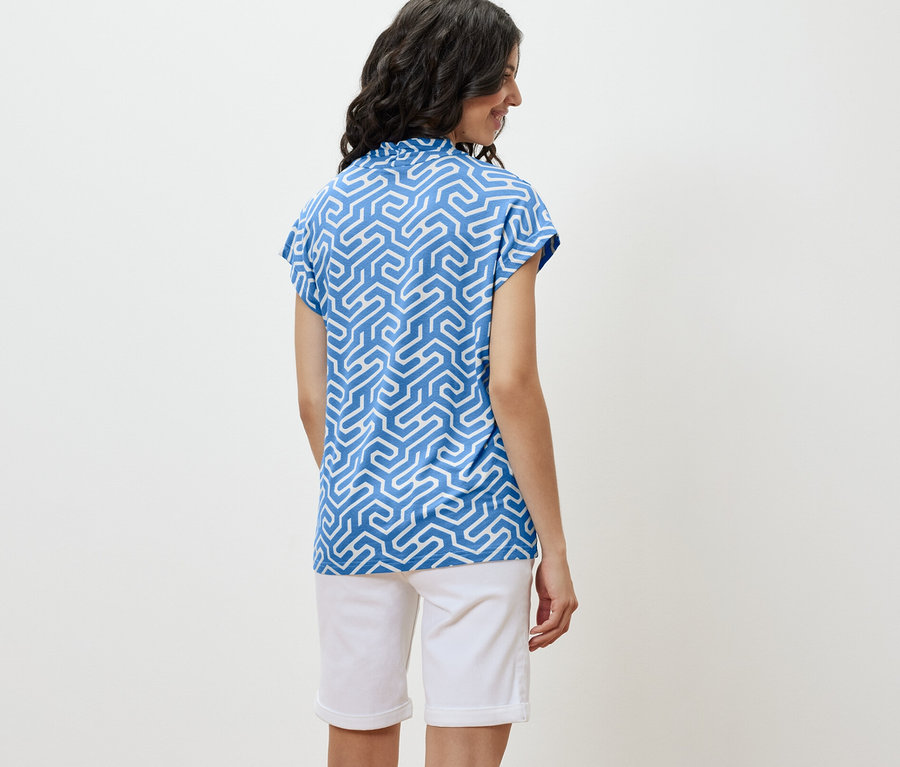 Kadın mavi V yakalı bluz ve beyaz şort giyiyor.