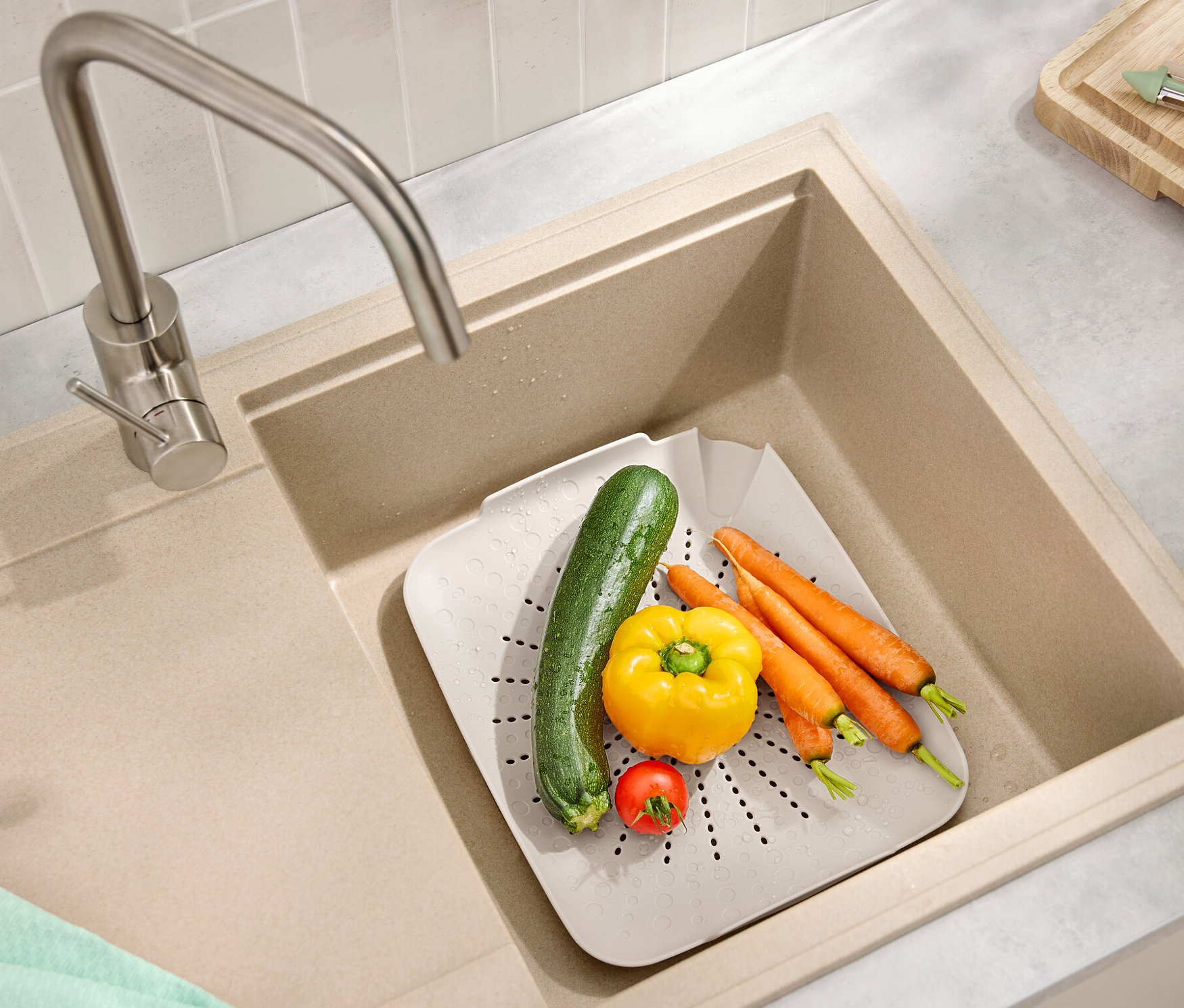 Lavabonun içinde havuç, biber, kabak ve domates bulunan düz bir lavabo süzgeci bulunmaktadır.