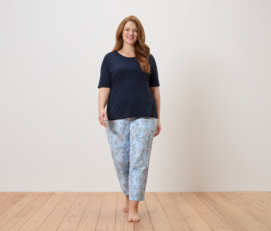 Kadın lacivert üst ve açık mavi desenli pantolonla yalın ayak yürüyor.