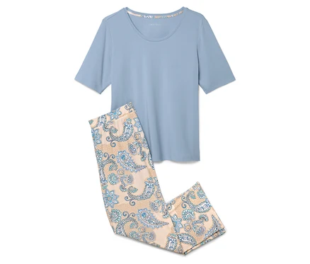 Açık mavi bir pijama üstü, mavi çiçek desenli açık kahverengi bir pijama altının yanında duruyor.