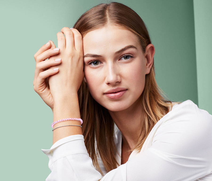 Bileğinde kesme cam taşlı bileklik olan bir kadının portresi.