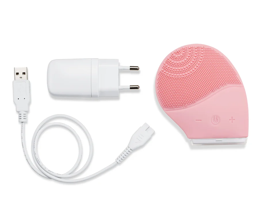 Pembe renkli elektrikli silikon yüz temizleme fırçası, şarj kablosu ve adaptörü ile birlikte.