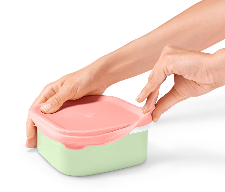 Eller pembe kapaklı ve yeşil tabanlı emaye beslenme kutusunu açıyor.