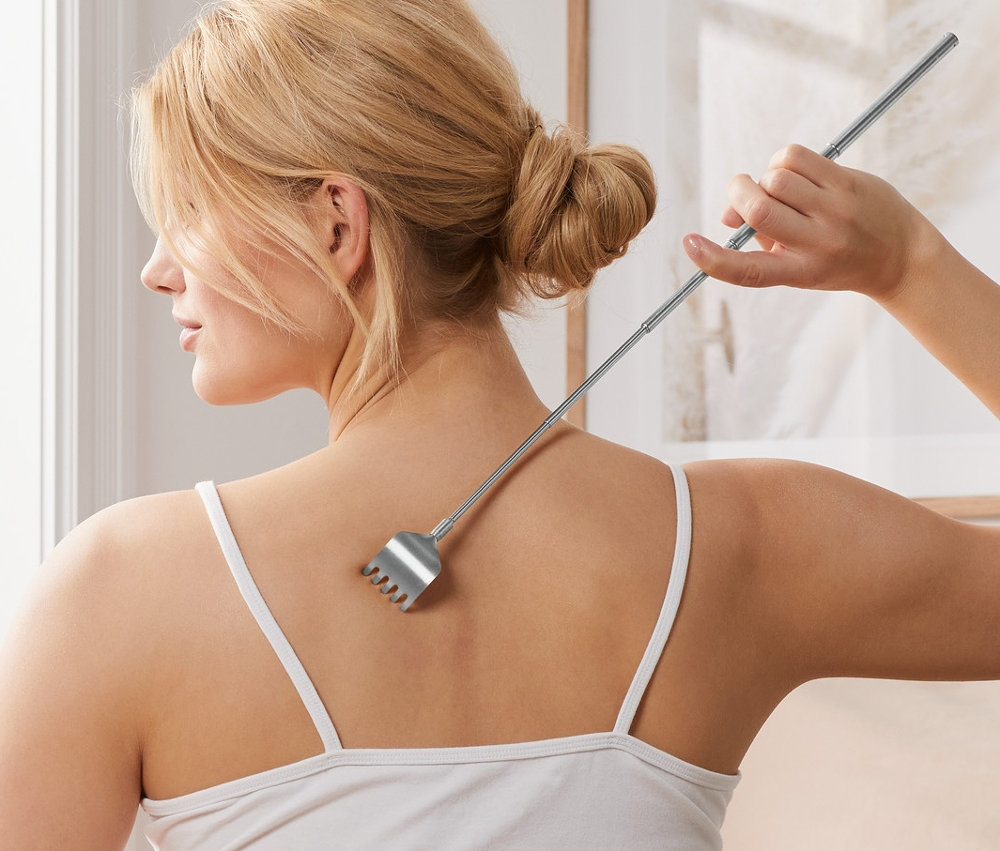 Kadın yatakta oturuyor ve Sırt Kaşıyıcı ile sırtını kaşıyor.