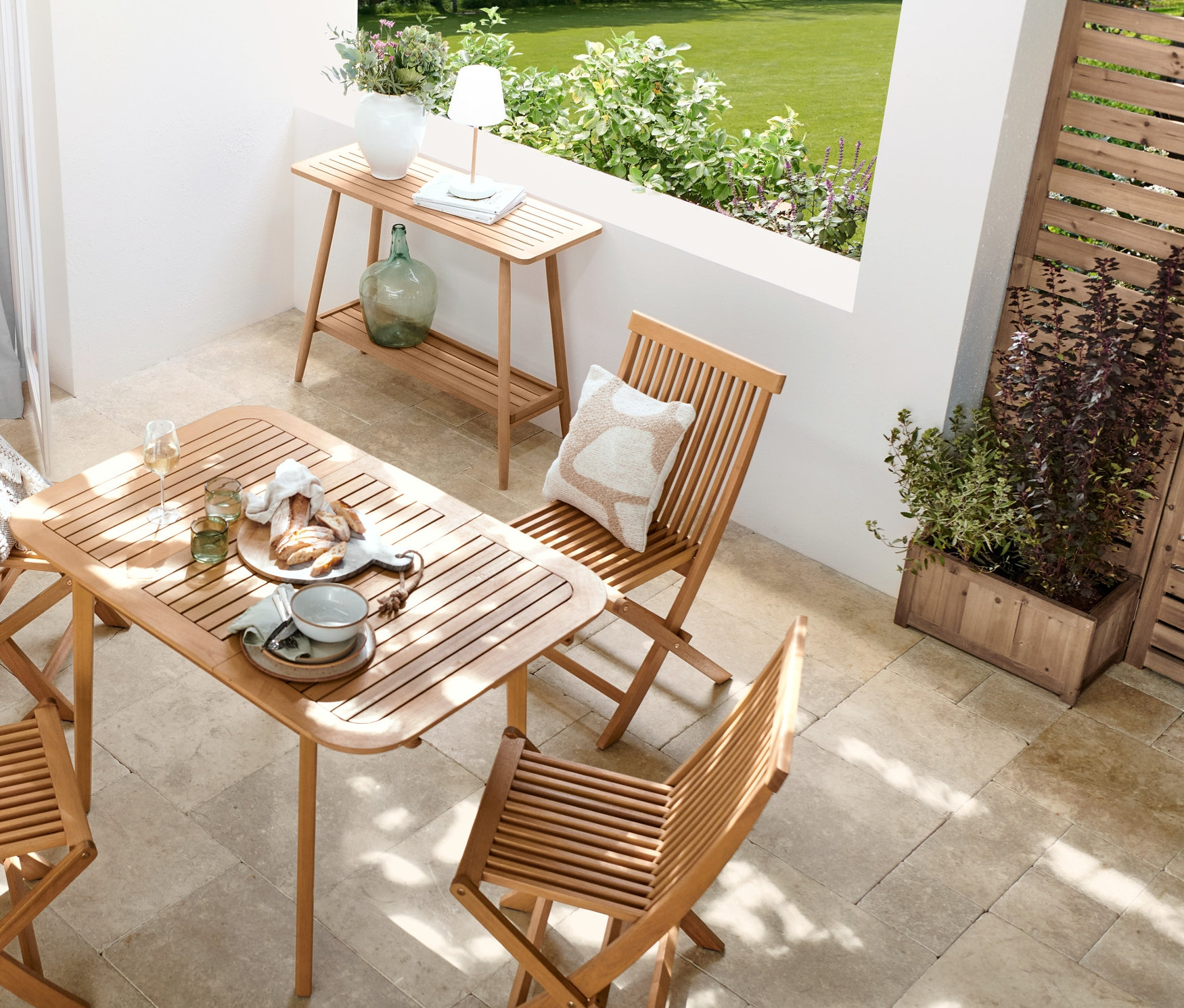 Açık havada yemek alanı, uzatılabilen masaya sahip 5 parçalı »Lenja« yemek masası takımı, ahşap görünümlü LED'li akülü masa lambası, saksılıklı »Tinus« paravan ve 2 katlı konsol sehpa ile düzenlenmiştir.