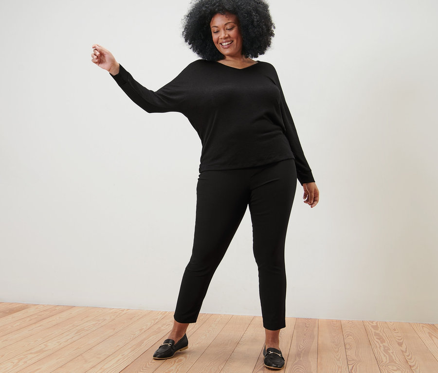 Kadın yarasa kol bluz ve siyah streç pantolonla poz veriyor.