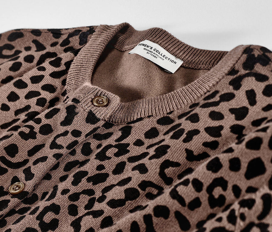 Siyah hayvan deseni ve düğmeleri olan kahverengi, baskılı ince örgü hırkanın yakın çekimi.