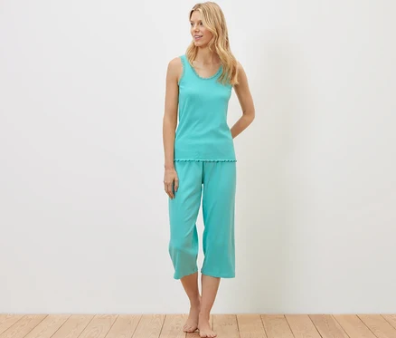 Sarışın bir kadın ayakta duruyor ve fitilli bir pijama takımı giyiyor.