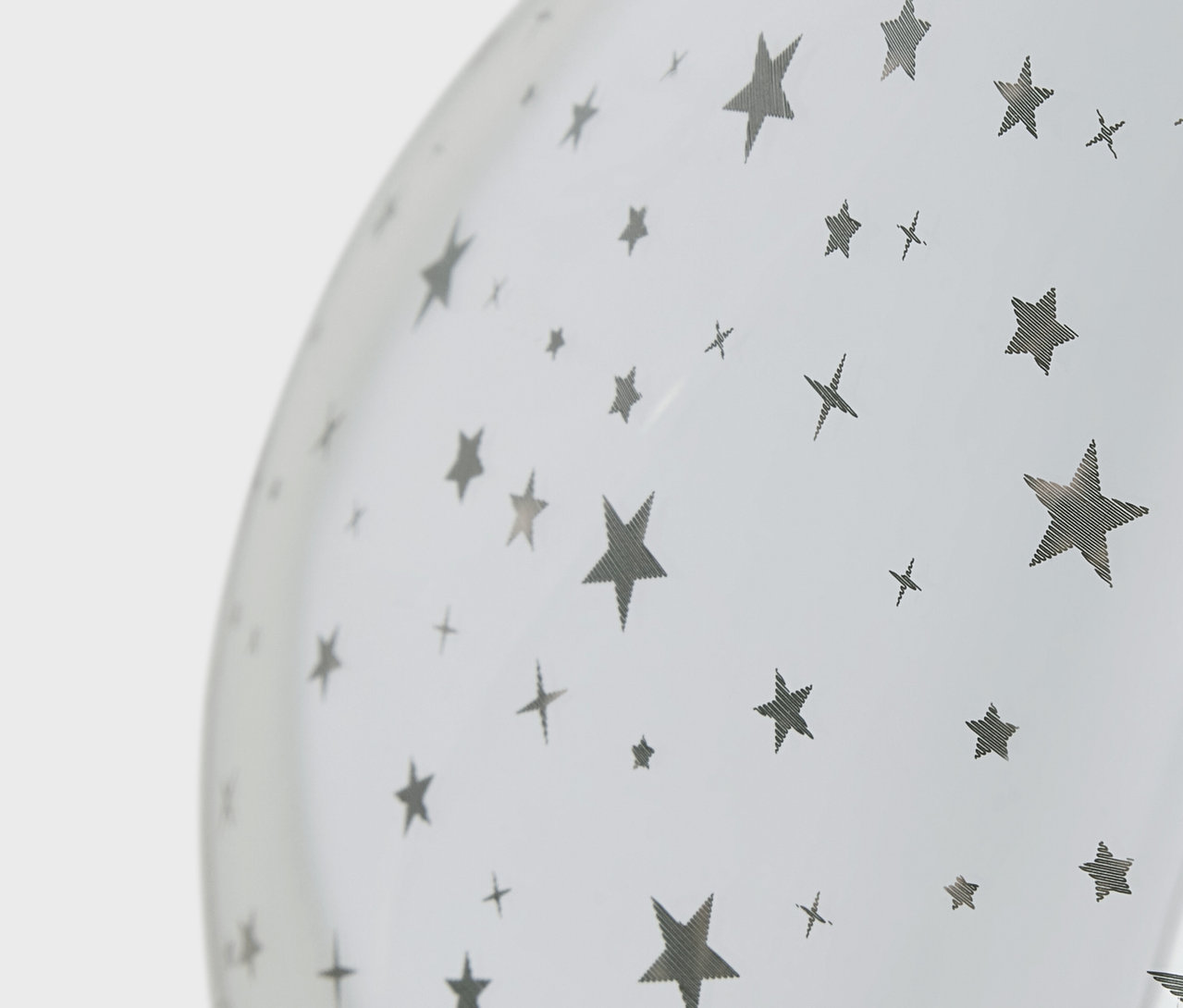 Gümüş yıldız ve çarpı desenli beyaz balonun yakın çekimi.