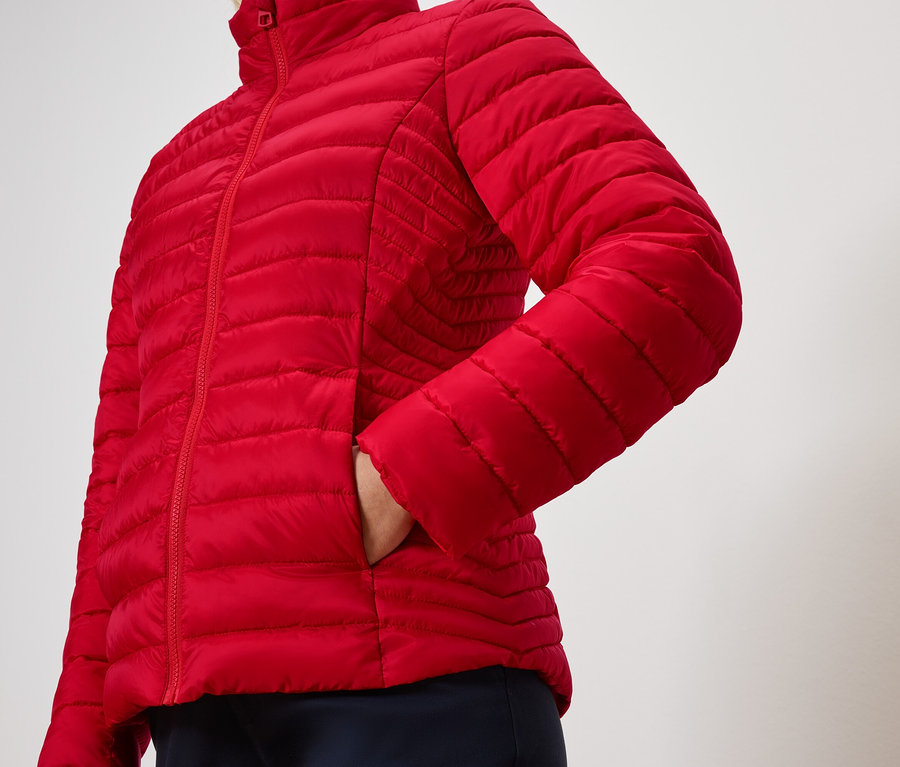 Bir kişi kırmızı kapitone bir ceketin cebinde elini tutuyor.